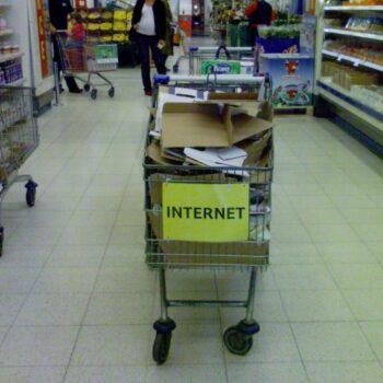 an image of a shopping cart full of scrap paper, cardboard, and other pieces of trash. A yellow piece of paper is on the front with the word "internet" in all caps.